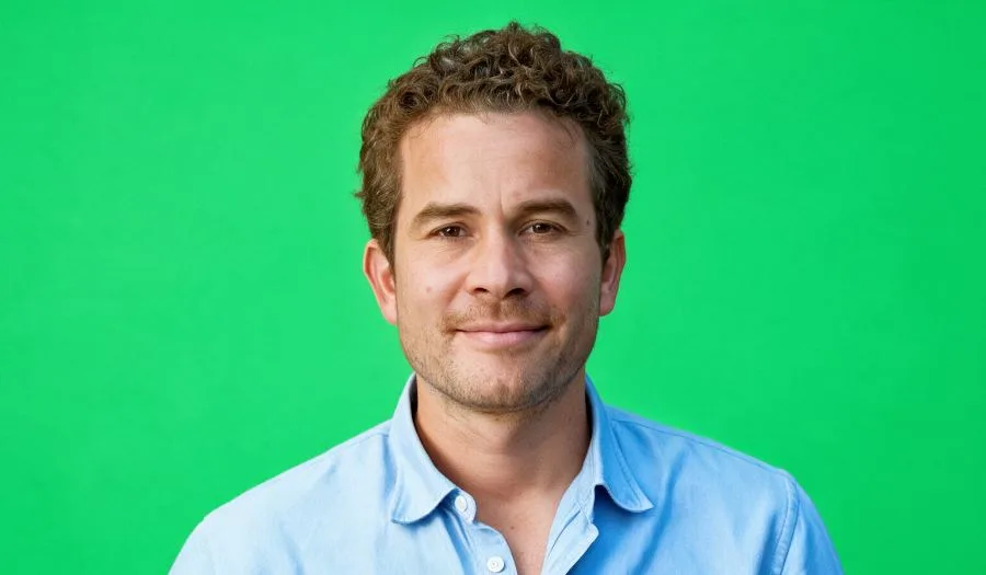 Portret van Guido Kloek tegen een groene achtergrond.